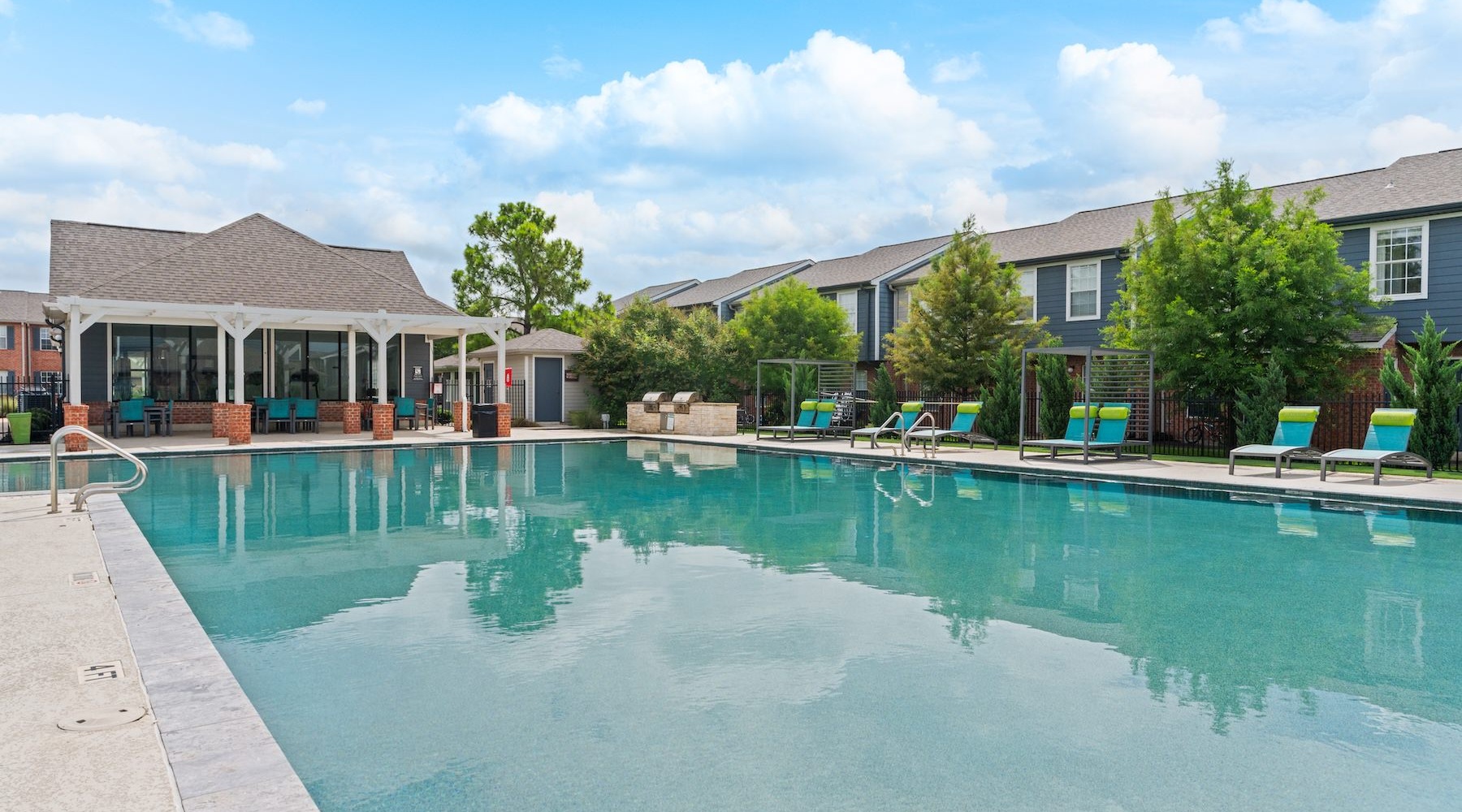a swimming pool with lounge chairs in a courtyard
